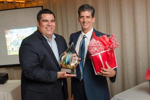 Two well dressed men holding rewards and smiling