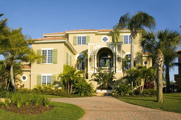Street view of a multi story yellow house accompanied by trees